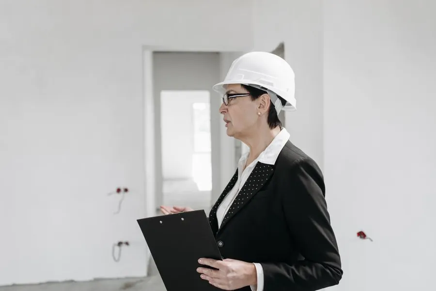 Building control inspector with a clipboard checking structural work in a stripped room