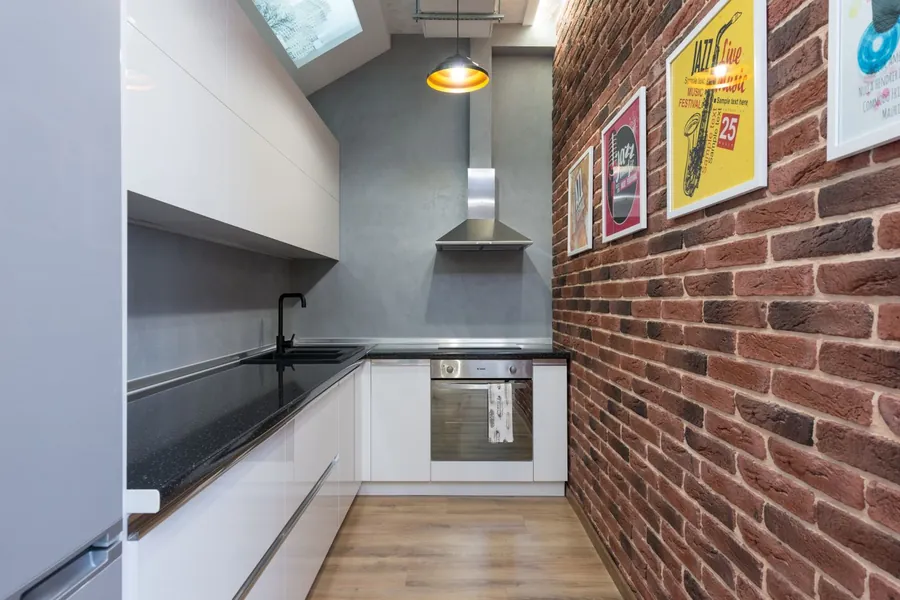Narrow galley kitchen with white units and exposed brick in a Liverpool terraced house