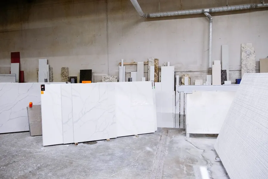 Full size quartz worktop slabs stood on racks at a stone yard, the kind of weight and length that makes delivery access a factor on a Waterloo kitchen fit