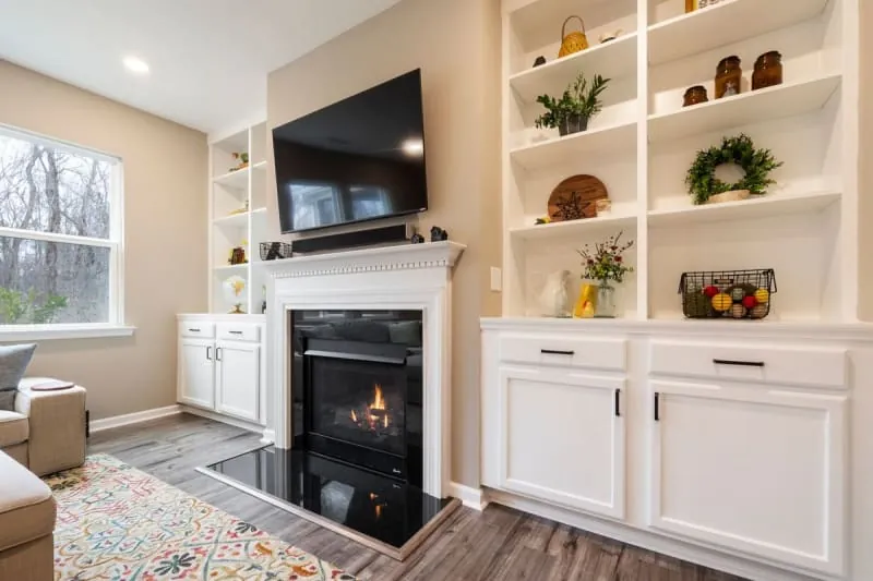 Living room alcove with built-in cabinets and open shelving beside a fireplace