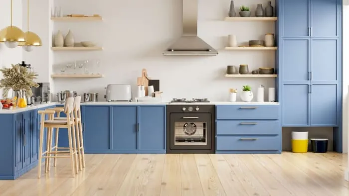 Blue and white kitchen with wooden floors and open shelving. Features oven, cabinets, counter with bar stools, and appliances.