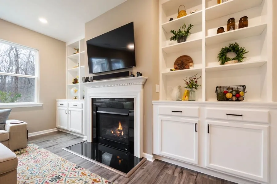 Living room fireplace flanked by fitted base cabinets with shelves above