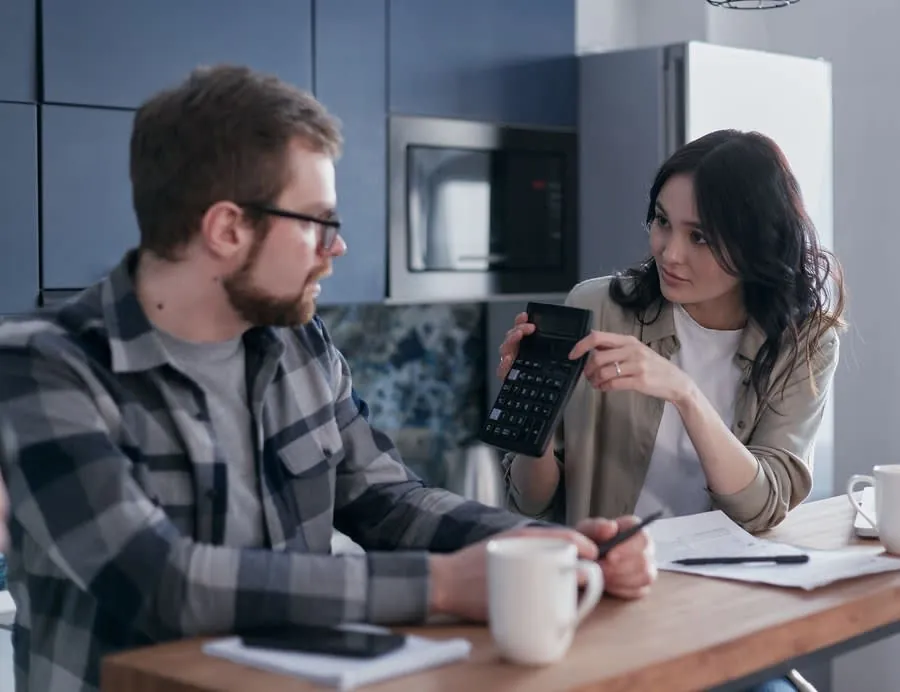 Couple going through household costs with a calculator at a kitchen table