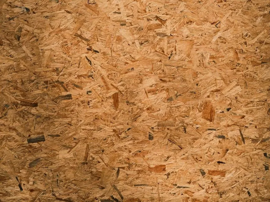 Close-up of an engineered wood panel showing the pressed chips and strands used in kitchen carcasses