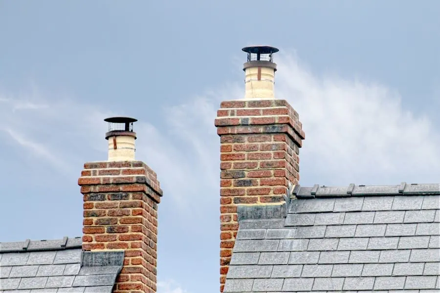 Traditional brick chimneys on a slate roof of an English terraced house