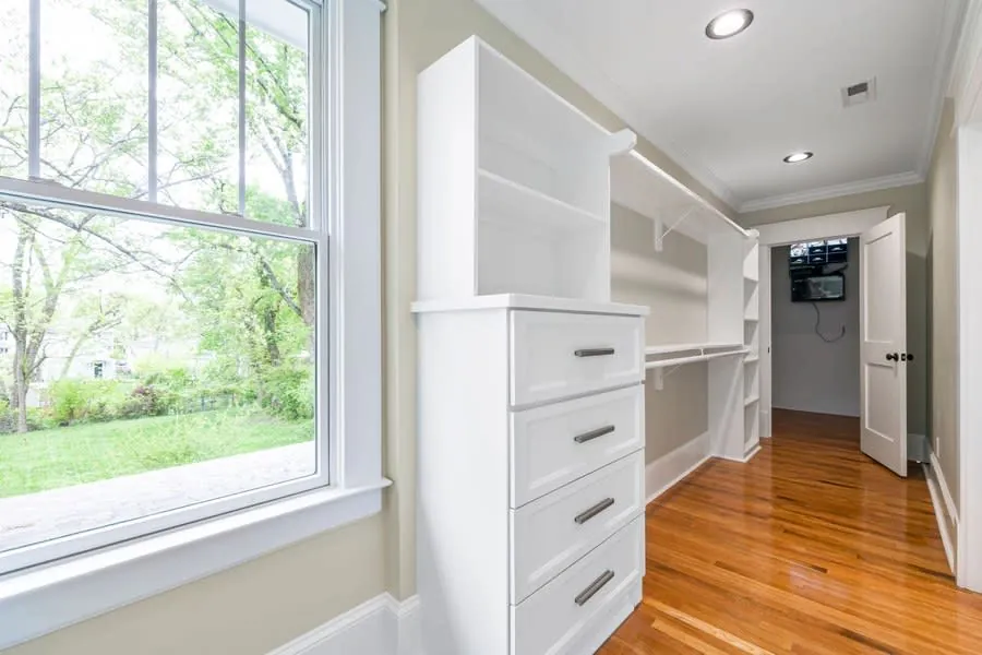 Walk-in wardrobe with white shelving and a bank of drawers