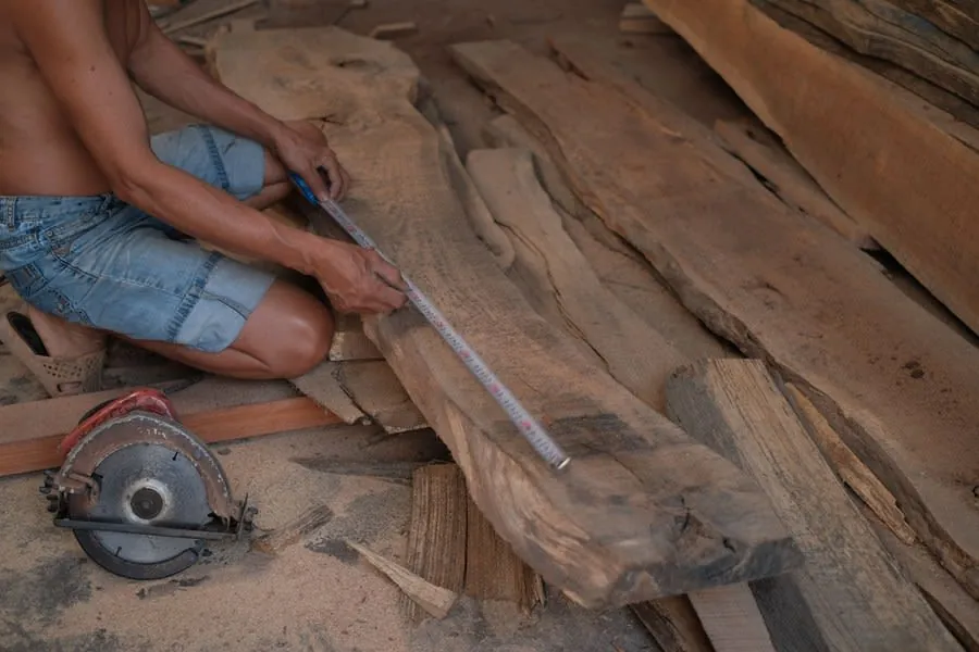Joiner measuring a timber board with a tape measure before cutting