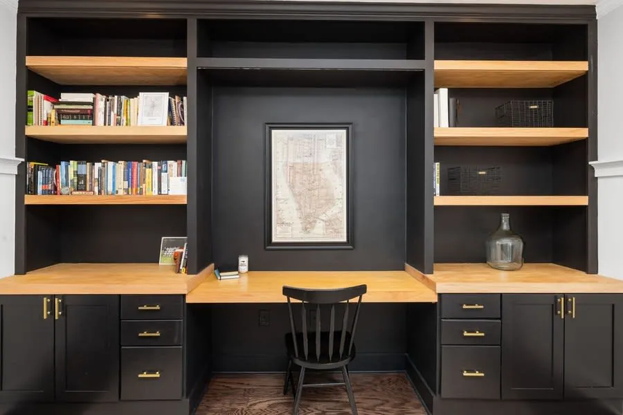 Home office with a built-in desk and dark timber bookshelves