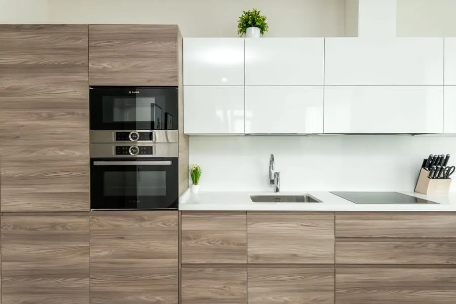 White and wood minimalist kitchen showing doors, worktop and built-in storage