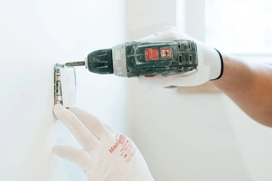 Electrician drilling out a wall box for a new kitchen socket circuit