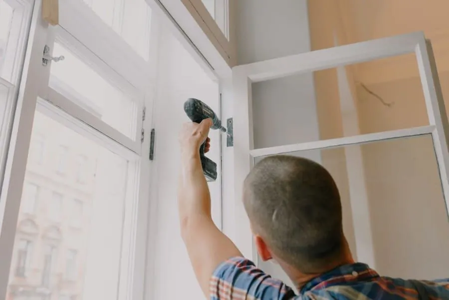 Fitter using a cordless screwdriver to assemble kitchen cabinet units in a Liverpool property