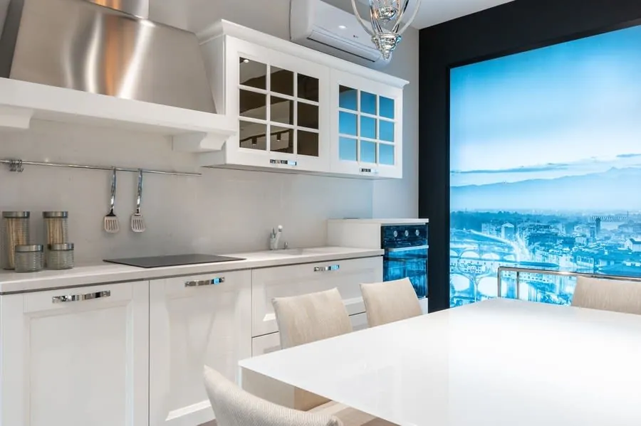 Kitchen with cooker hood, white cupboards and dining table by the counter