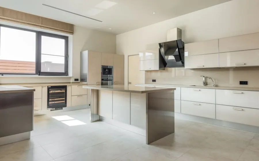 Modern white kitchen with island, cabinets, large window, and stainless steel appliances