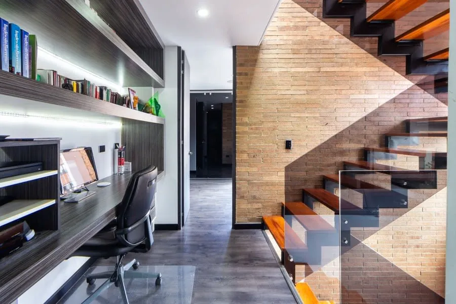 Compact fitted desk built into a nook beside a wooden staircase