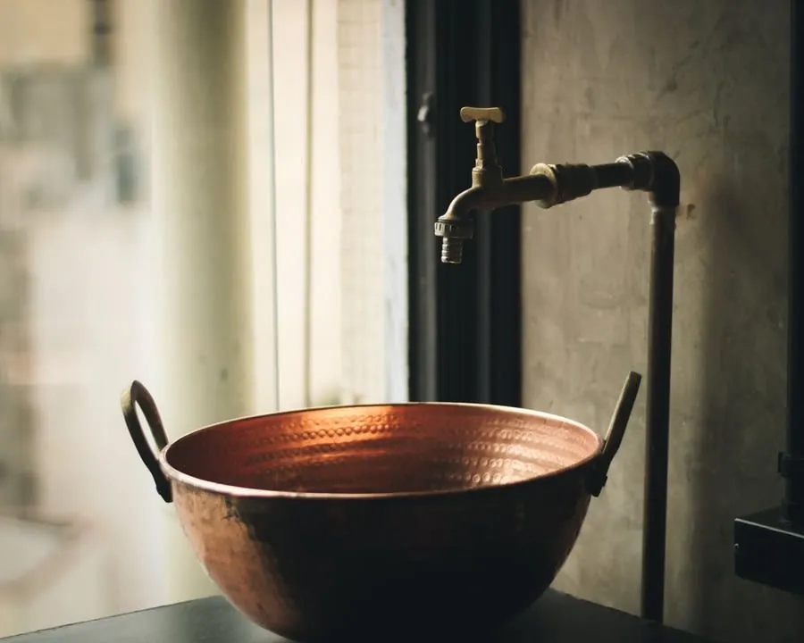Old brass tap and copper vessel representing original pipework in a Liverpool terraced house