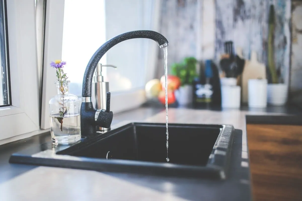 Chrome mixer tap running into a dark sink in a Liverpool kitchen supplied with soft water