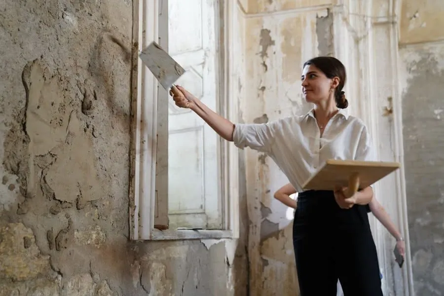 Renovator replastering an old solid wall in a Victorian property before new kitchen units go in
