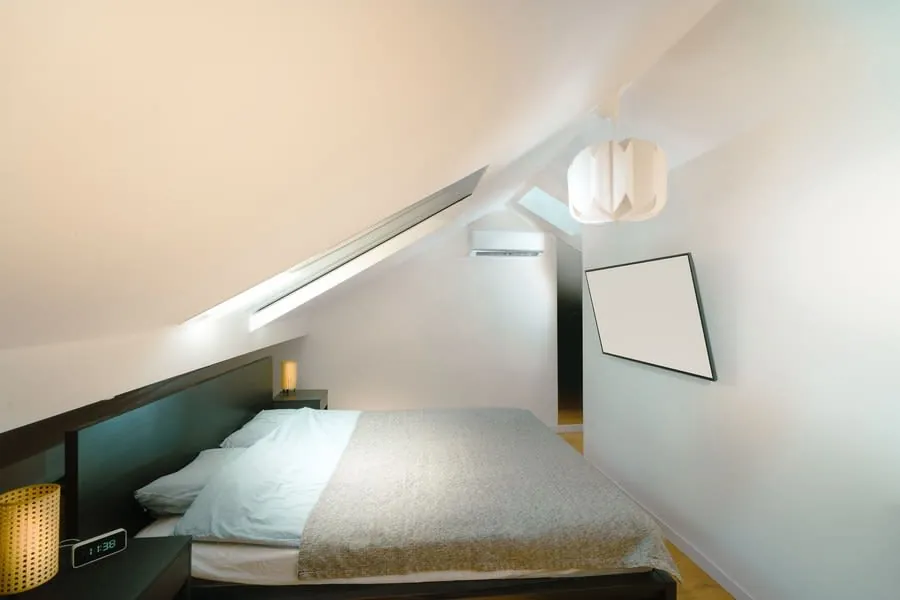 Loft bedroom with a sloping ceiling and minimal furniture under the roof pitch