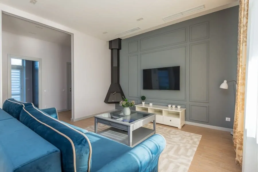 Living room media wall with a wall-mounted TV above a blue sofa