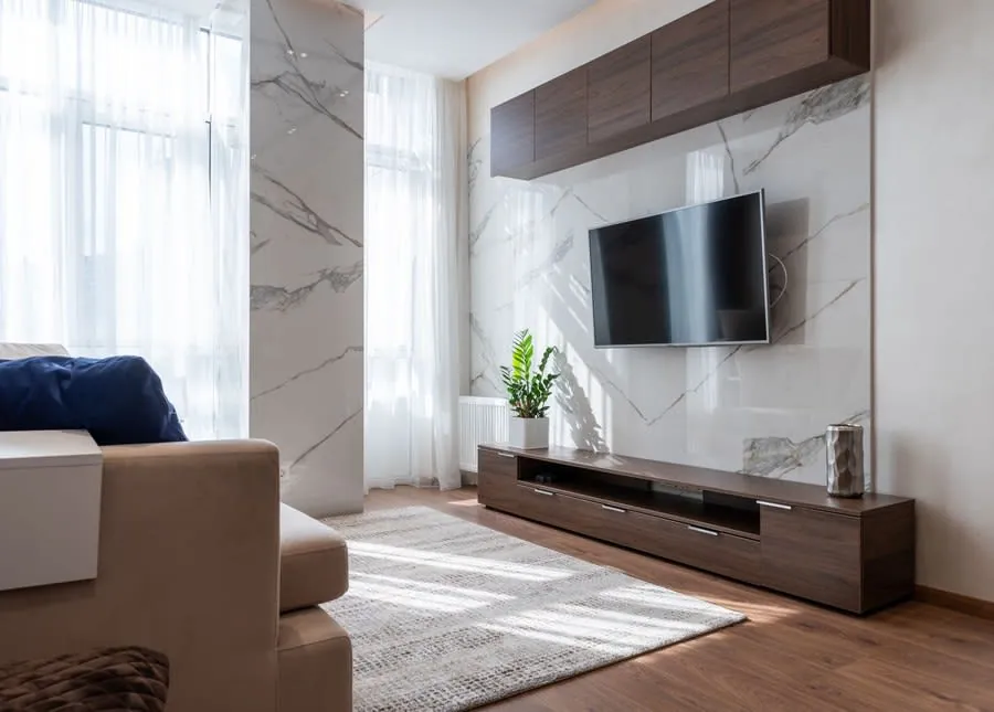 Wall-mounted television between built-in wooden cabinets in a bright living room