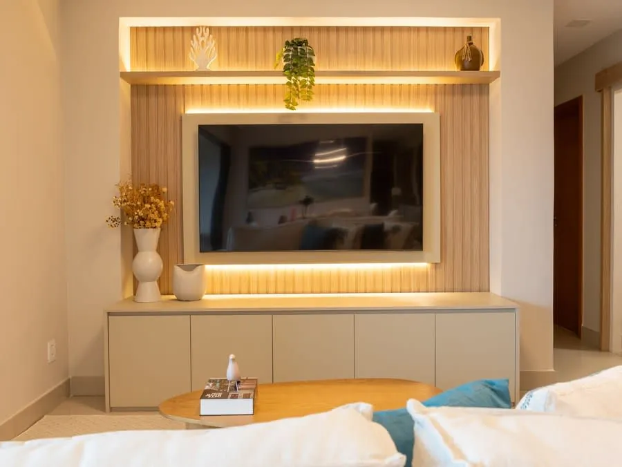 Modern living room entertainment setup with lit shelving and neutral decor
