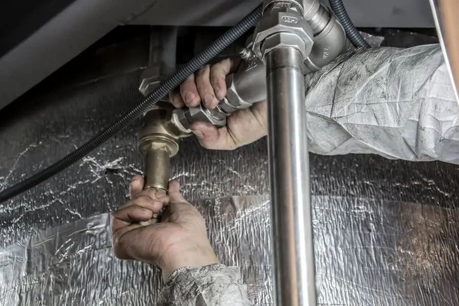 Plumber connecting new pipework under a kitchen sink during a Liverpool refit