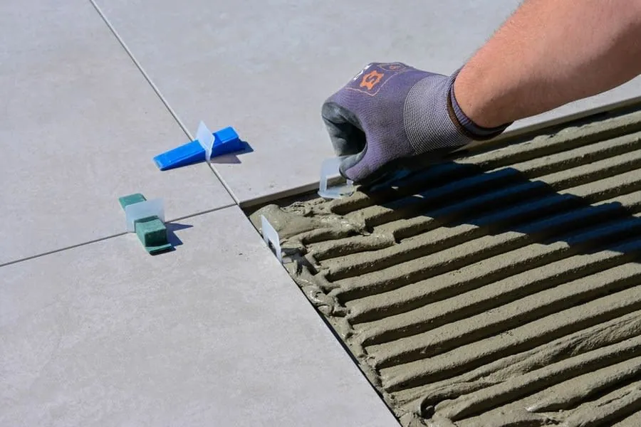 Tiler laying porcelain floor tiles with levelling clips in a Liverpool kitchen