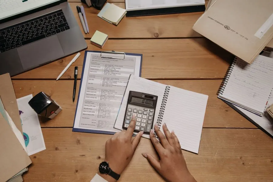 Hands checking figures on a written quotation with a calculator