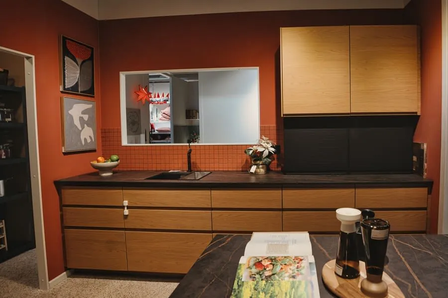 Modern kitchen with wood cabinets, black countertop, sink, window, and coffee maker on a table