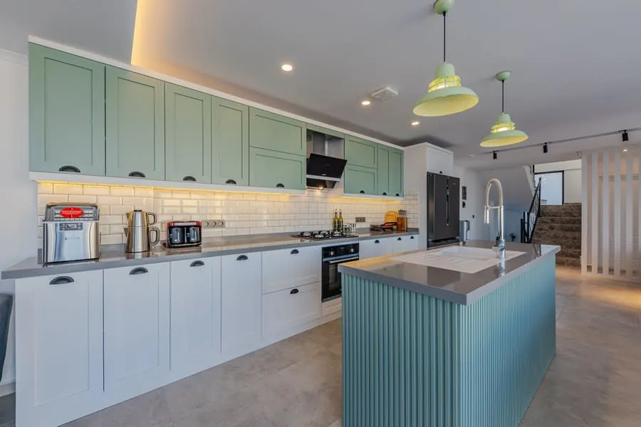 Bright modern kitchen with mint cabinets, white counters, pendant lights, and a central island