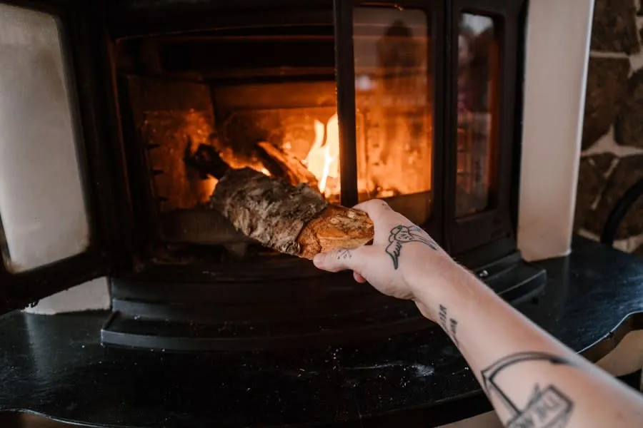 Hand placing a log into a burning fireplace in a home living room