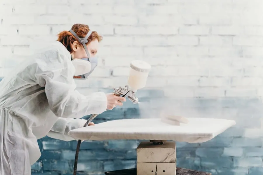 Furniture panel being spray finished in a workshop with protective gear