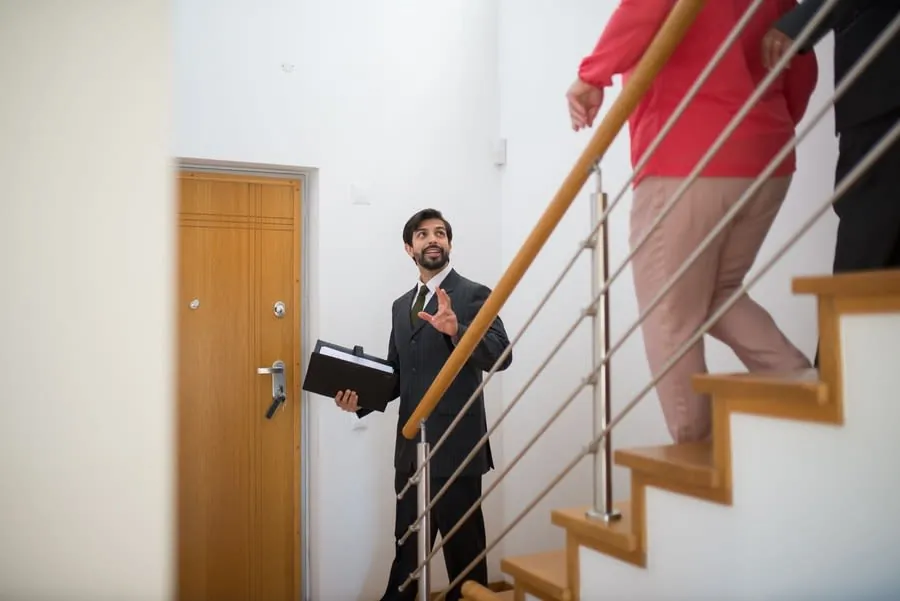 Estate agent showing buyers around the staircase and hallway of a home