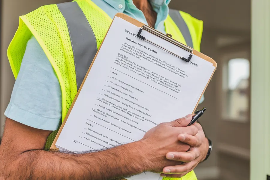 Contractor with a clipboard checklist surveying a Liverpool home before quoting for a utility room