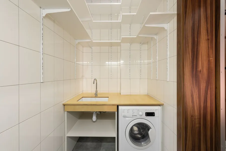 Utility space with washing machine and open shelving showing ventilation and appliance layout in a Liverpool home