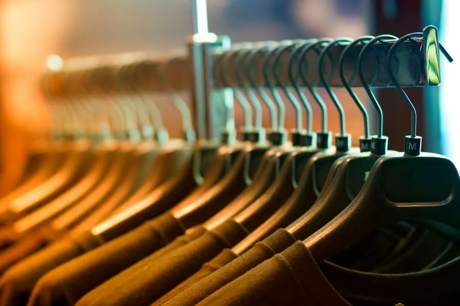 Row of clothes hanging on a rail with wooden hangers
