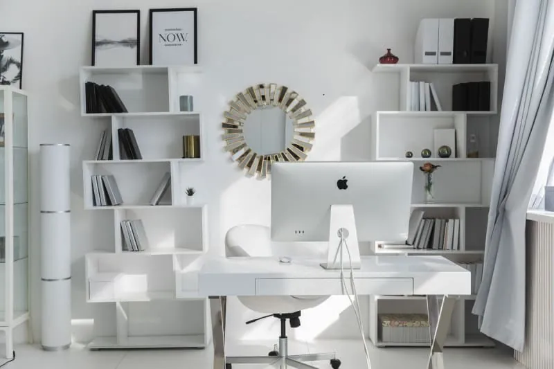 Bright home office with white fitted shelves and desk