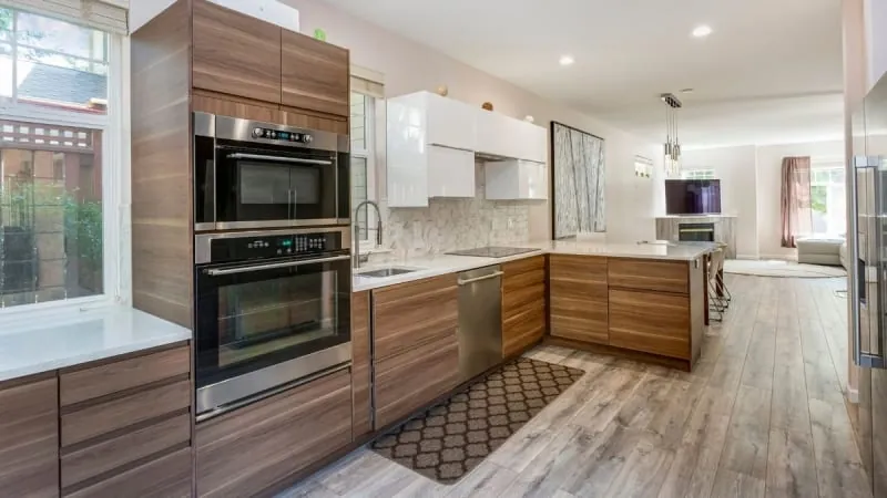 Modern kitchen with wood cabinets, stainless steel appliances, and a white countertop.