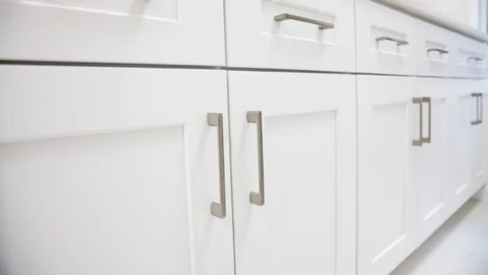 White kitchen cabinets with silver handles.