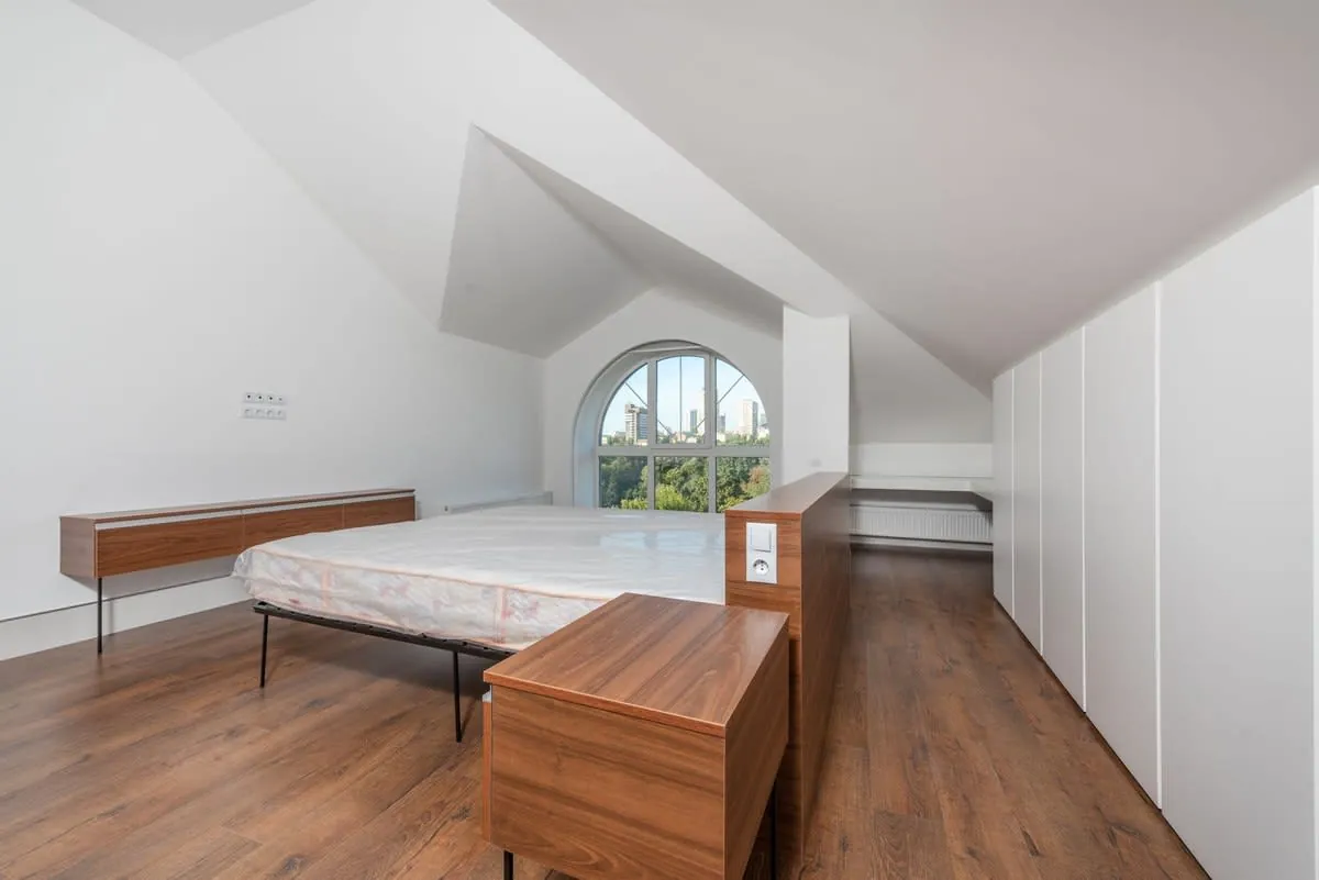 Loft conversion bedroom with a sloping ceiling and fitted storage built into the eaves