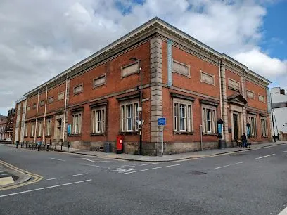 Red brick building at a street corner with many windows, blue signs, and a red mailbox.