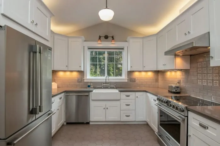 White kitchen with stainless steel appliances, white cabinets, and window.
